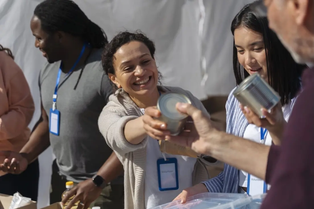 Woman wearing volunteer tag being handed a can. Represents user of VeryConnect's charity fundraising software.