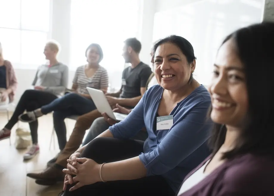 People sitting in circle as and smiling. Represent users of VeryConnect's community mentoring software.