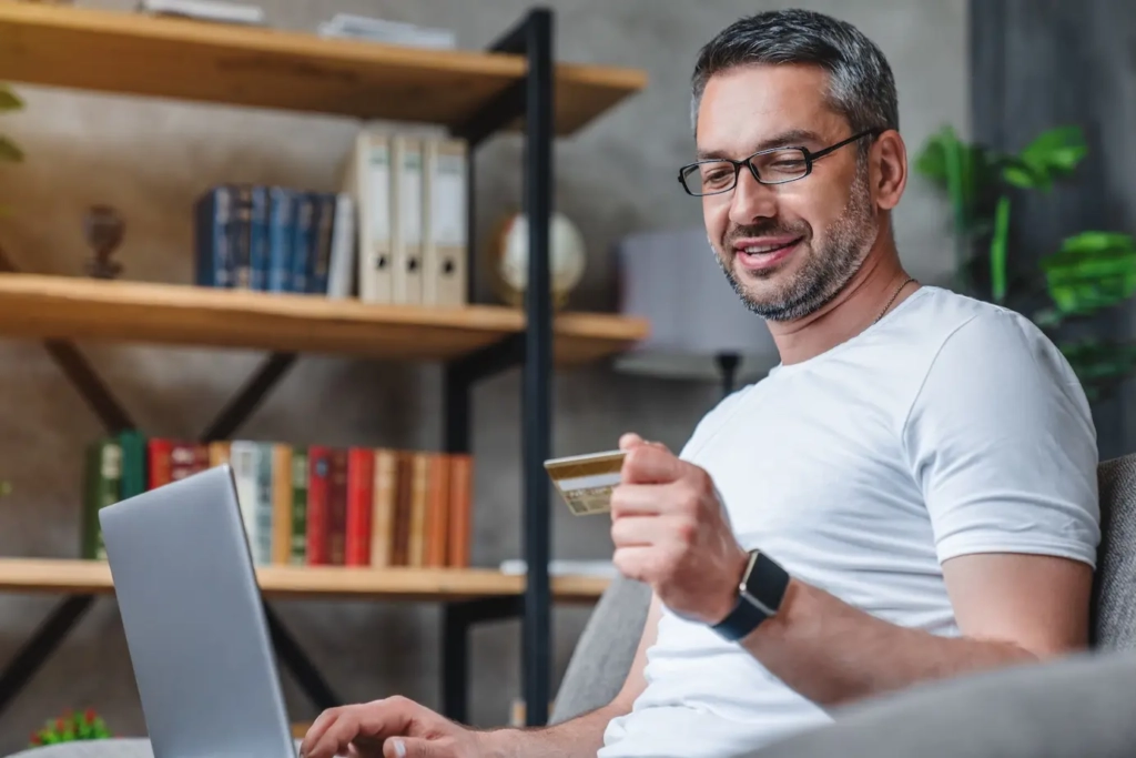 Man holding payment card looking at laptop. Represents user of VeryConnect's recurring membership billing software.
