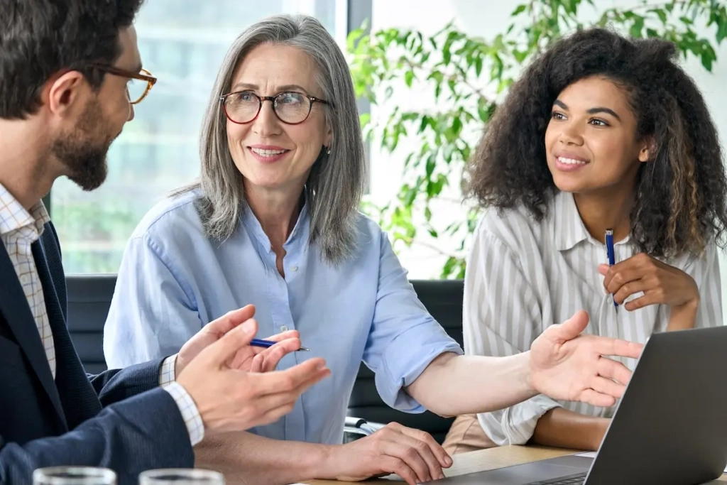 Woman showing her coworkers her laptop screen. Represents user of VeryConnect's CRM with Email Marketing