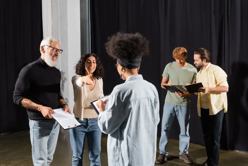 Group of people backstage in a theatre reading a script. Represents users of VeryConnect's theatre membership software.