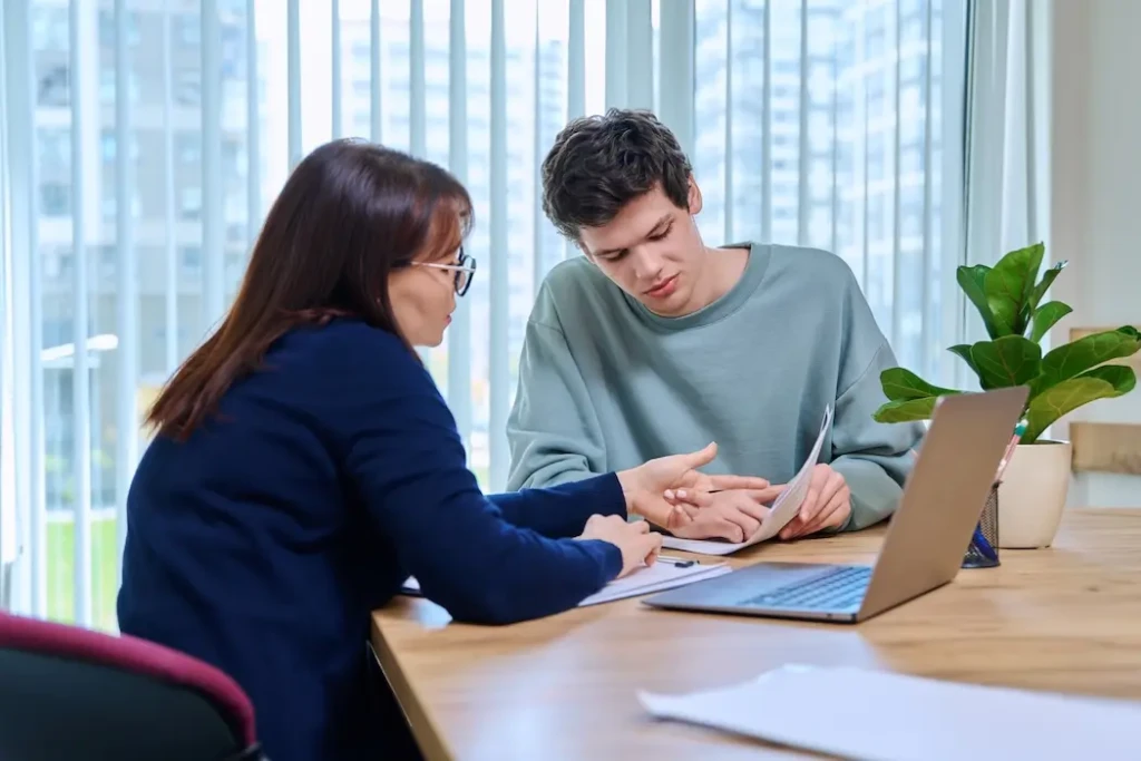 Women and teenage boy sitting at laptop. represents a mentoring session scheduled on VeryConnect's youth mentoring software.