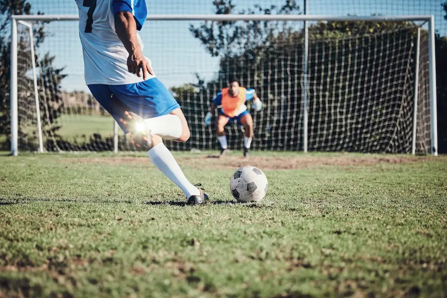 Person kicking football towards goal. Represents user of VeryConnect's soccer / football club software.