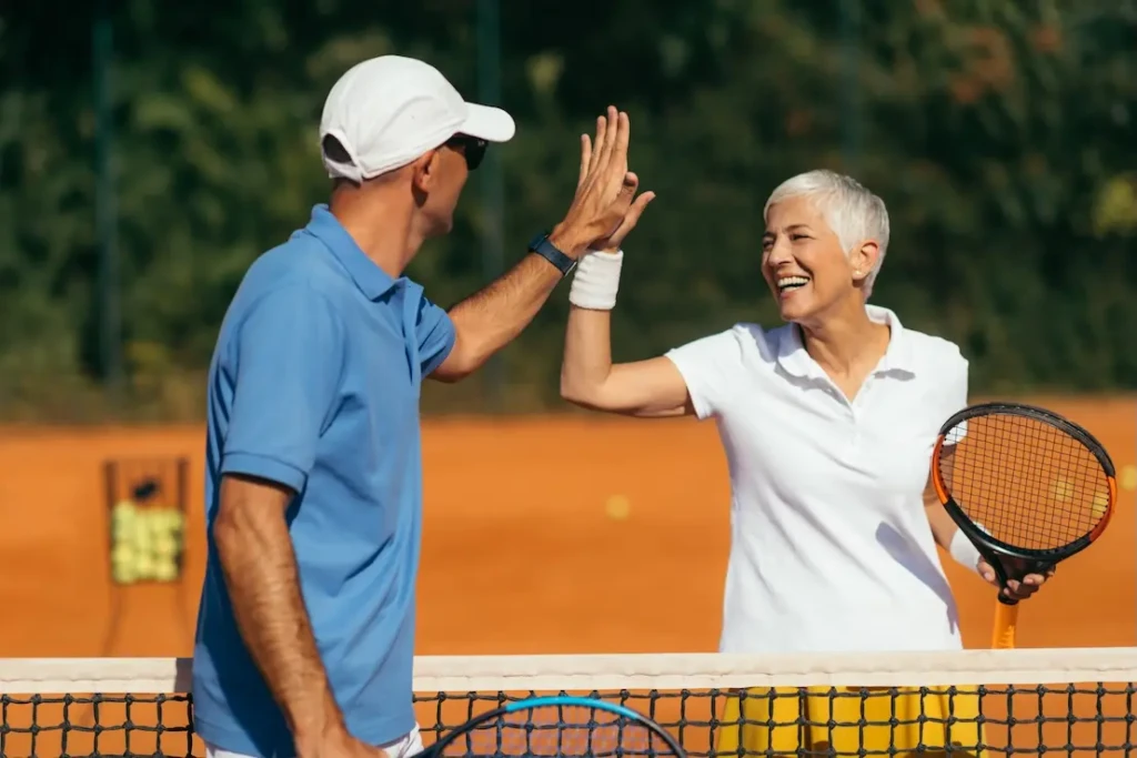 Two tennis players high fiving over the net. Represents users of VeryConnect's tennis club membership software.