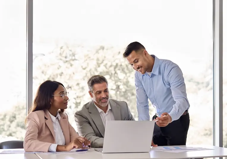 Three people at desk, all looking at one laptop. Represents users of VeryConnect's CRM LMS integration.