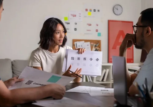 People at desk, showing papers with images. Represents users of VeryConnect's art society membership software.
